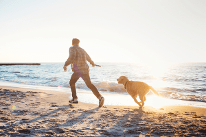 Man walking dog on beach - Sunrise CBD